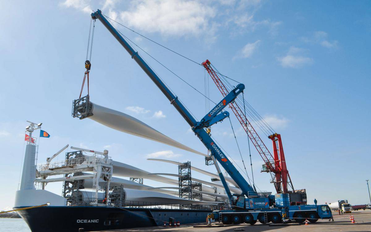 Two cranes discharging wind turbine blades from a vessel